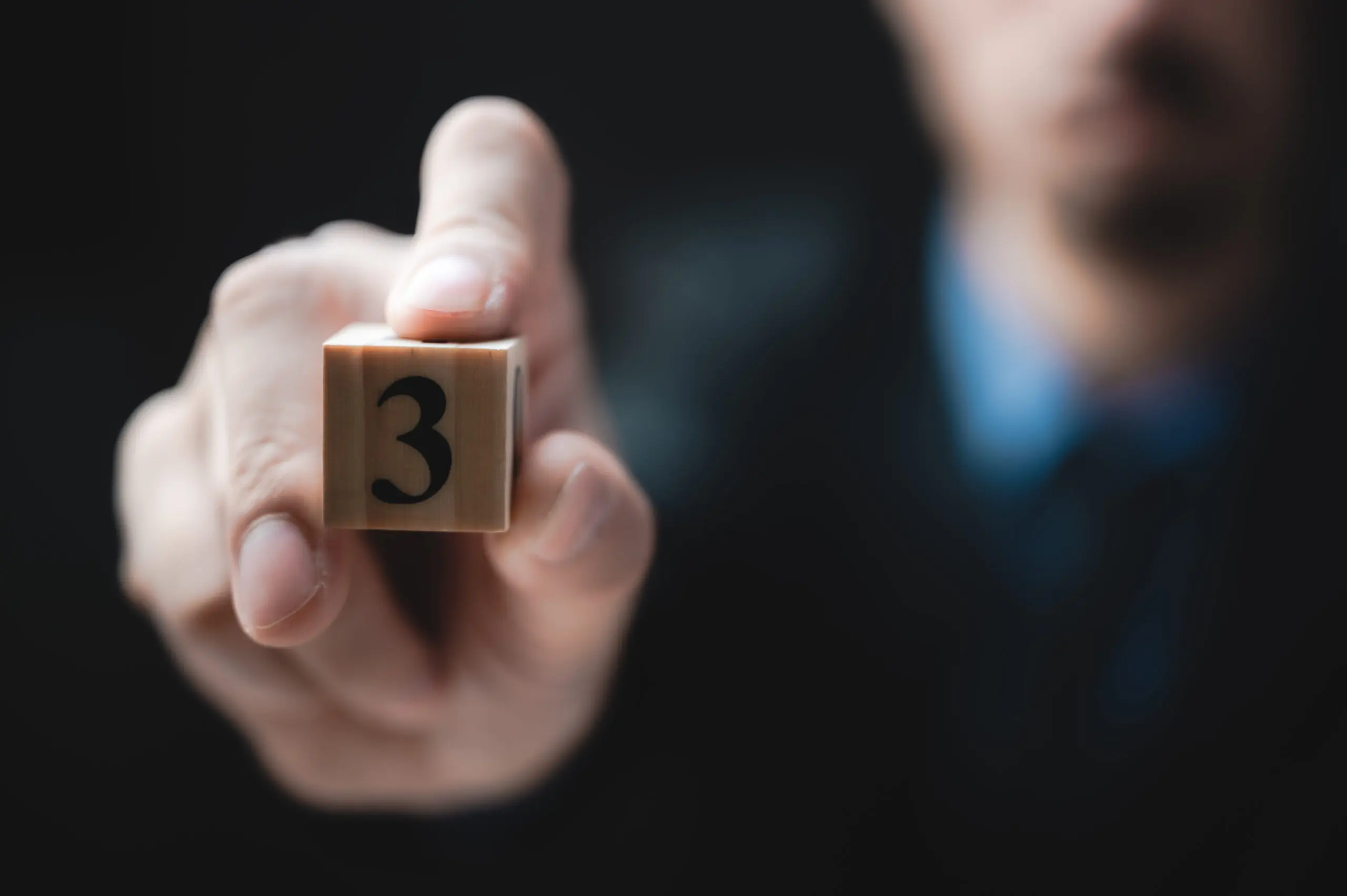 a man holding a block with the number "3" on it to represent the 3 c's of addiction